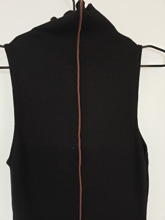 Black ribbed knit waistcoat hanging on a hanger, with a vertical brown line in the centre, on a white background.