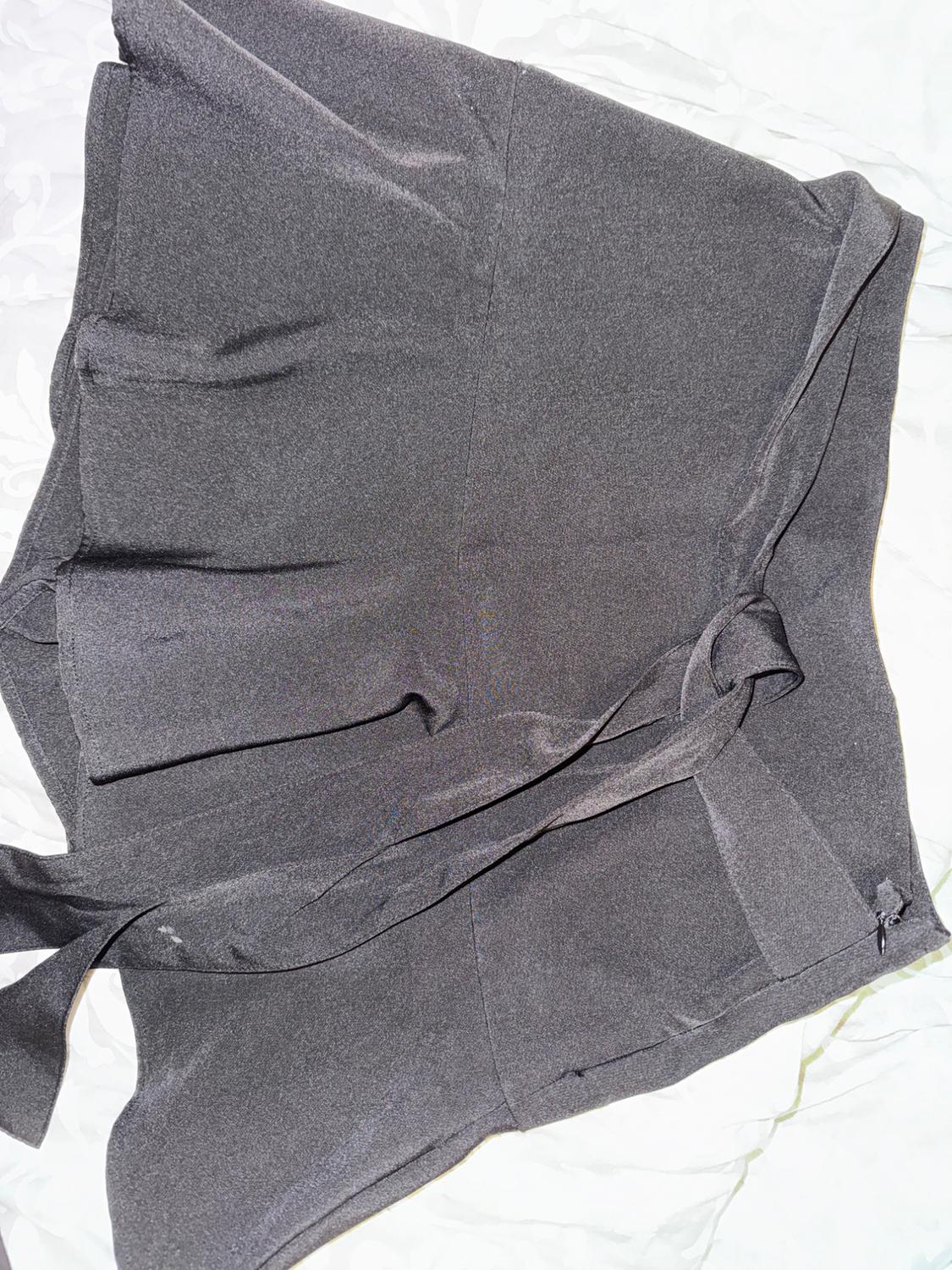 Grey shorts with a belt on a white background. Fabric with a soft texture and a light drape.