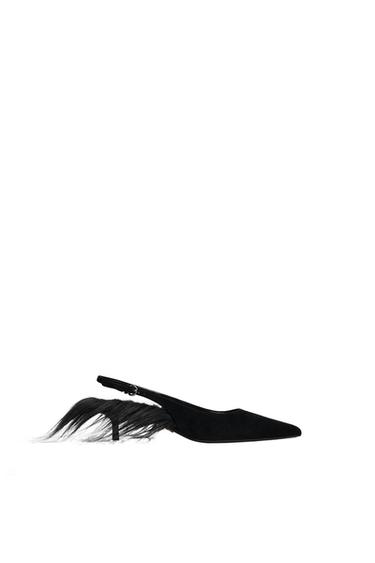 Black low-heeled shoe with feather design on the heel, on a white background.