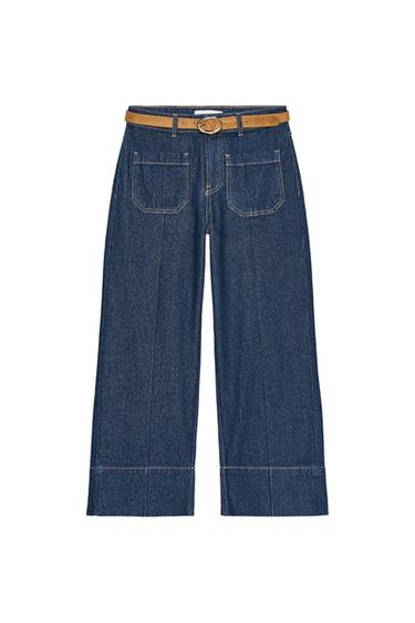 Front view of wide-leg, cropped blue jeans, with brown belt and front patch pockets.