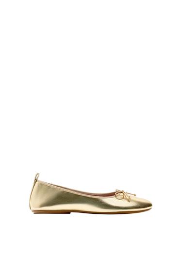 Metallic gold ballet flat with a small bow on the front and a pull tab on the back. Minimalist side view on a white background.