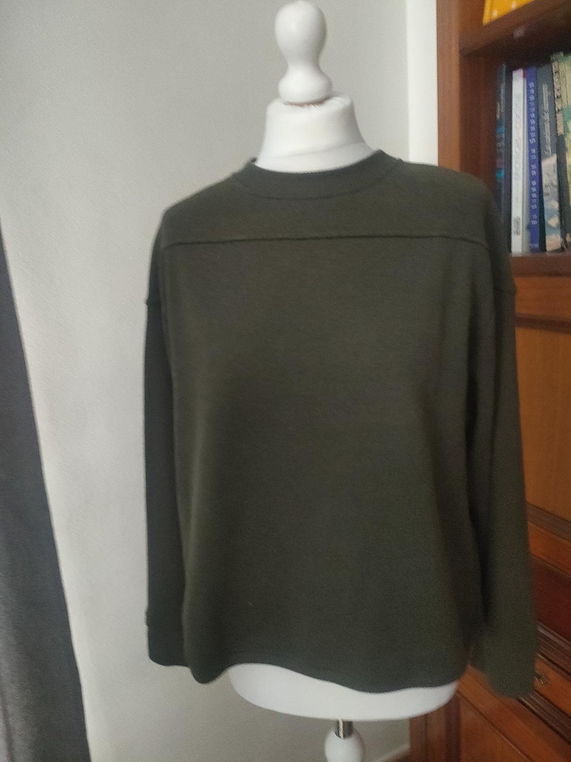 Front view of a dark green crew-neck, long-sleeved jumper.