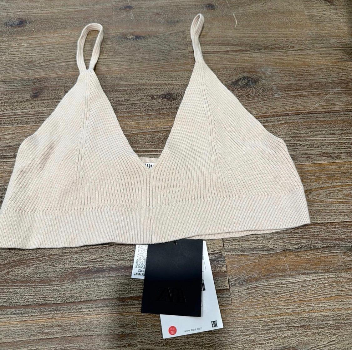 Beige ribbed knit cropped top with a V-neck on wood. Tags with the text ZARA, www.zara.com, EAC, 7302.
