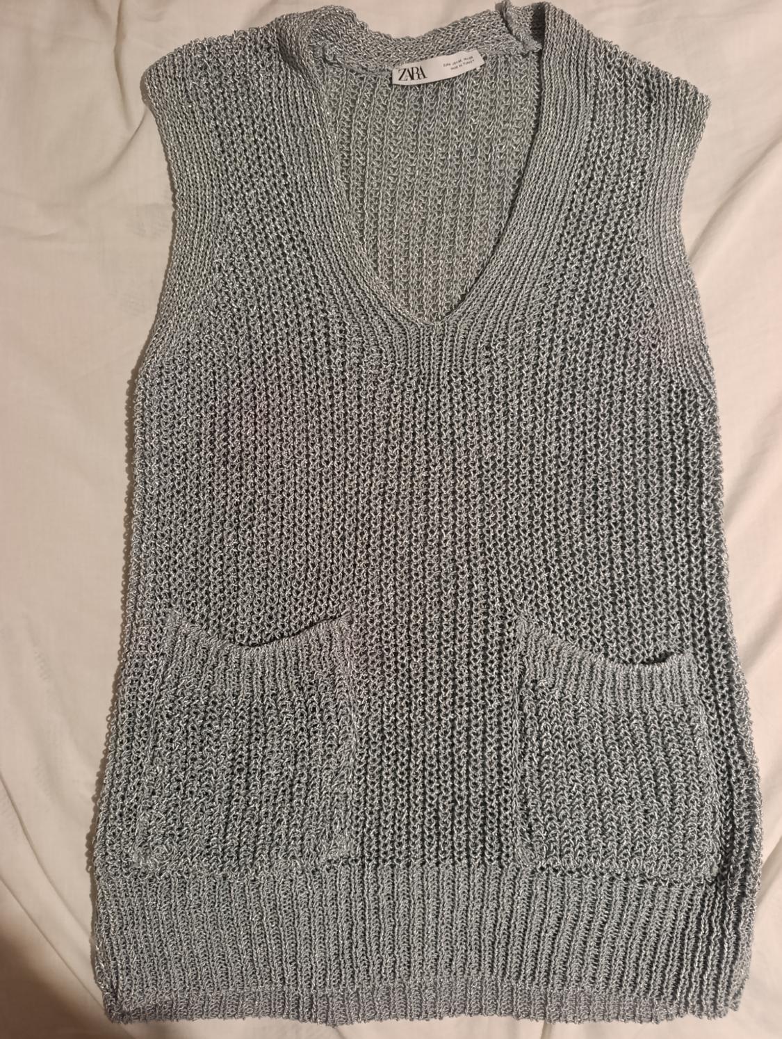 Grey knitted V-neck waistcoat with two front pockets. Visible label with the text "ZARA". White background.