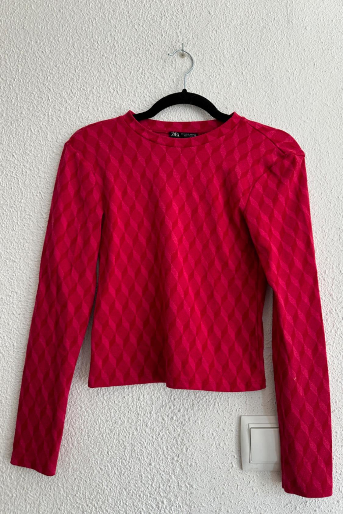 Front view of a red sweater with a geometric pattern and long sleeves.