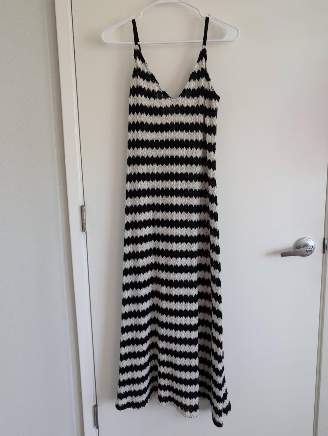Black and white horizontal striped knit maxi dress with thin straps and a V-neck, hanging on a white door.
