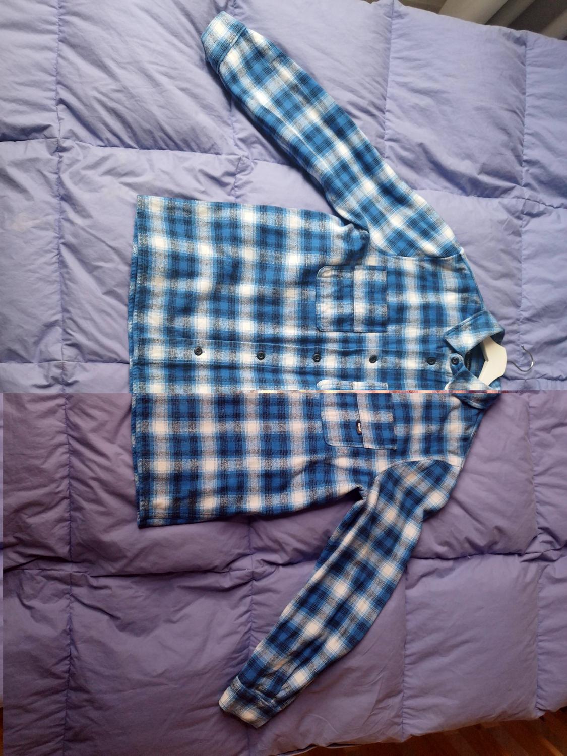 Blue and white checked shirt with buttons, placed on a purple duvet.