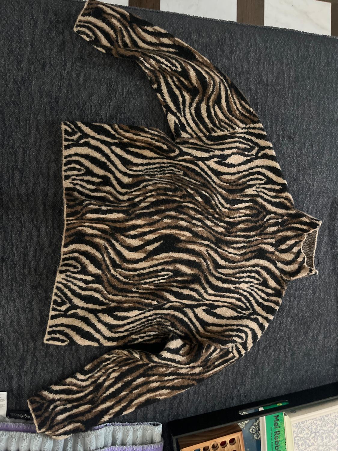 Long-sleeved black, brown, and beige animal print sweater on a dark gray background. It reads "logobrands" and "Mel Robbi".