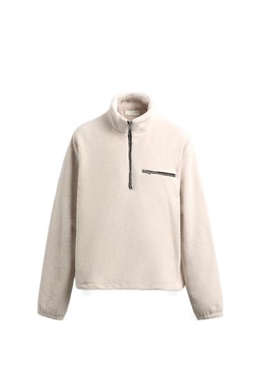Front view of a raw sweatshirt with a funnel neck, front zip, and zipped chest pocket. Long sleeves.