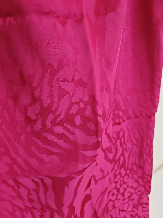Pink fabric with an embossed abstract pattern, showing a flowing and textured design.