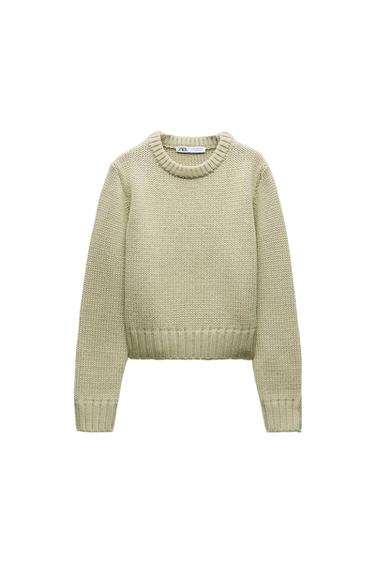 Light beige knit sweater with a round neck and long sleeves. Visible tag on the collar with the text "ZARA". White background.