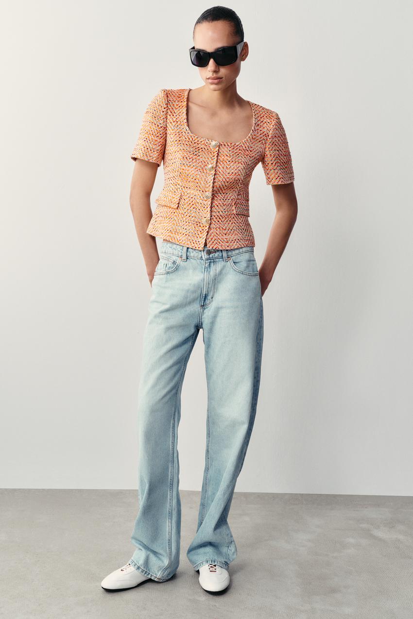 Textured orange top set, short sleeves, square neckline, front buttons and pockets, light blue jeans, and white sneakers.