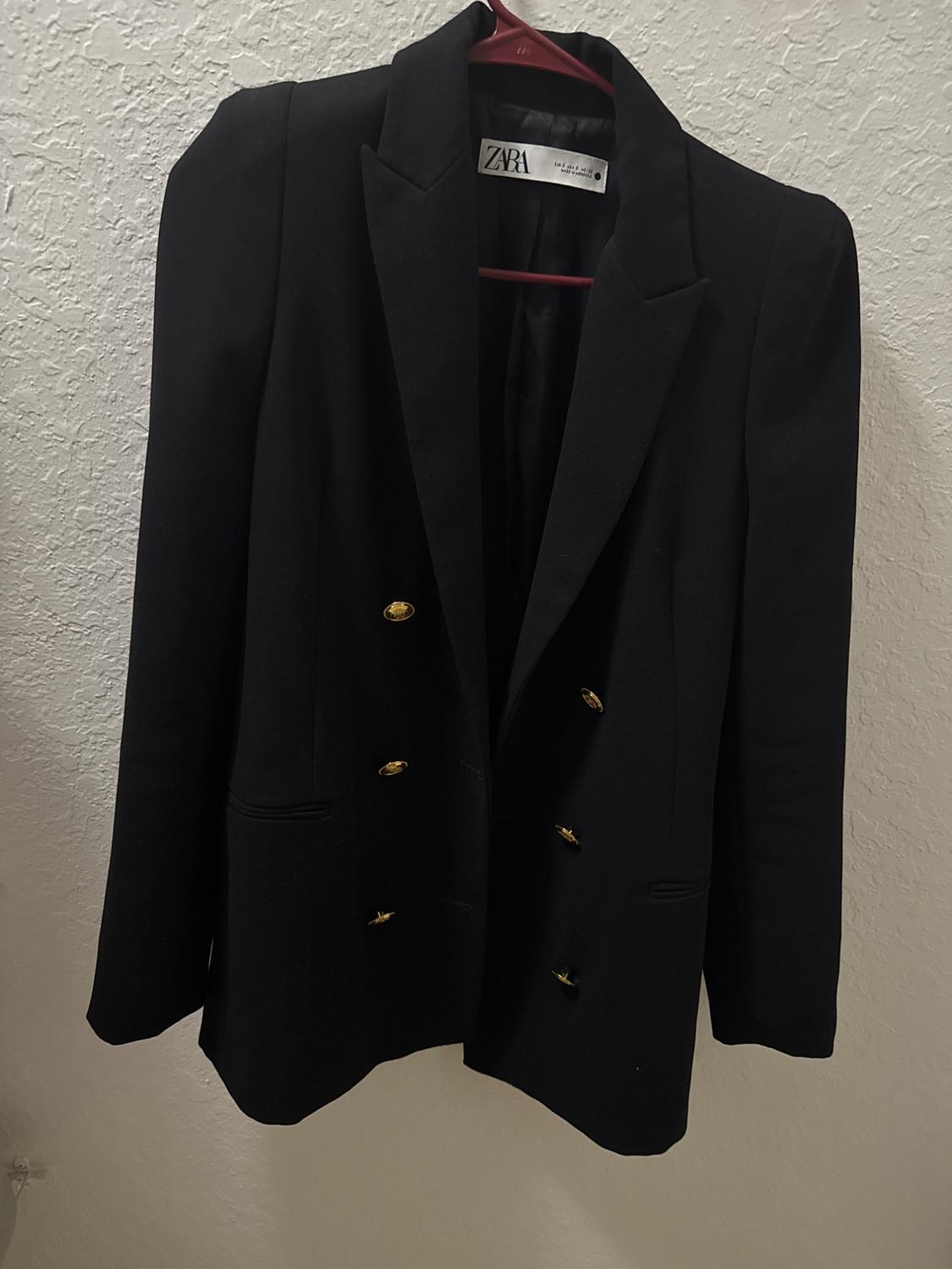 Front view of a black jacket with gold buttons and wide lapels.