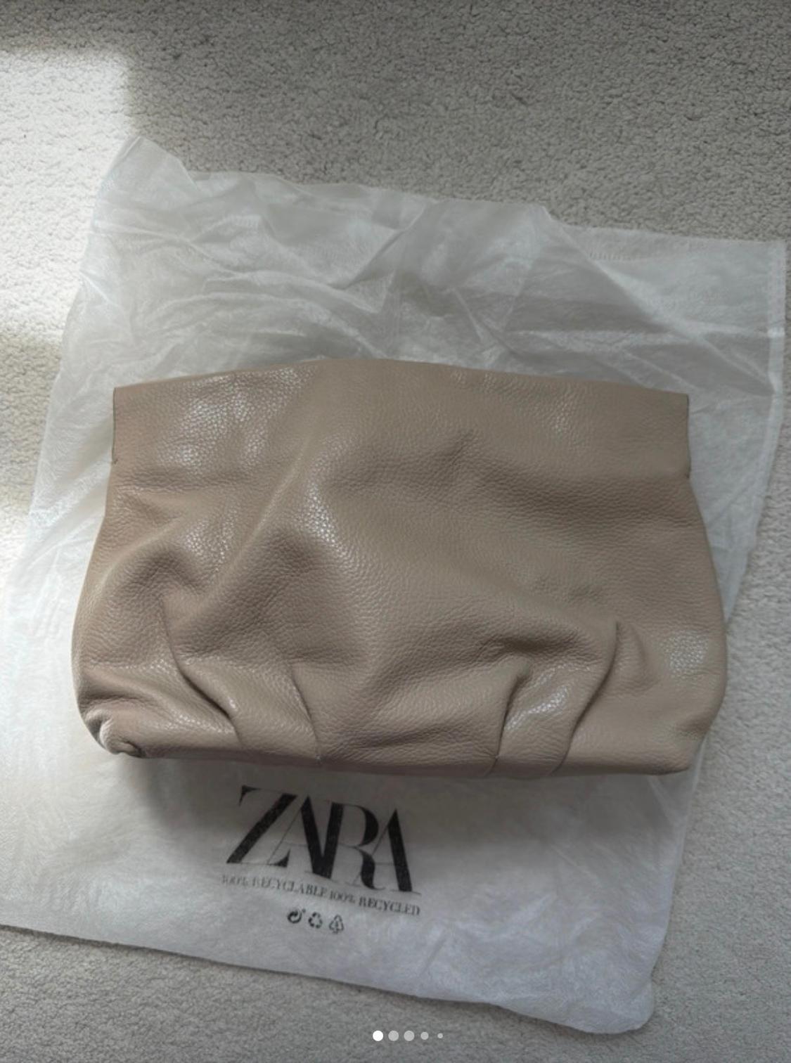 Beige bag over a white bag with the text ZARA 100% RECYCLABLE 100% RECYCLED, resting on a light-coloured rug in natural light.