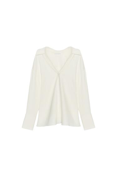 Front view of a shirt with a polo collar, V-neck and long sleeves finished with a cuff. Straight hem.