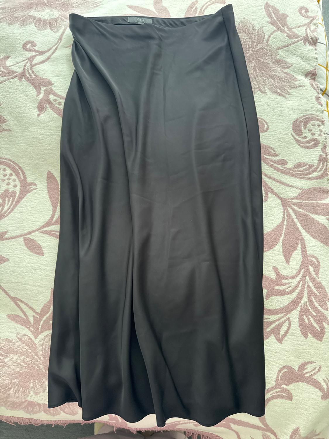 Black maxi skirt on a bedspread with a floral design in pink and white tones.