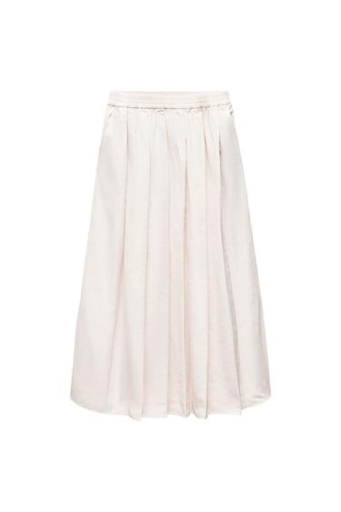 Front view of a cream-colored pleated skirt with an elastic waistband.