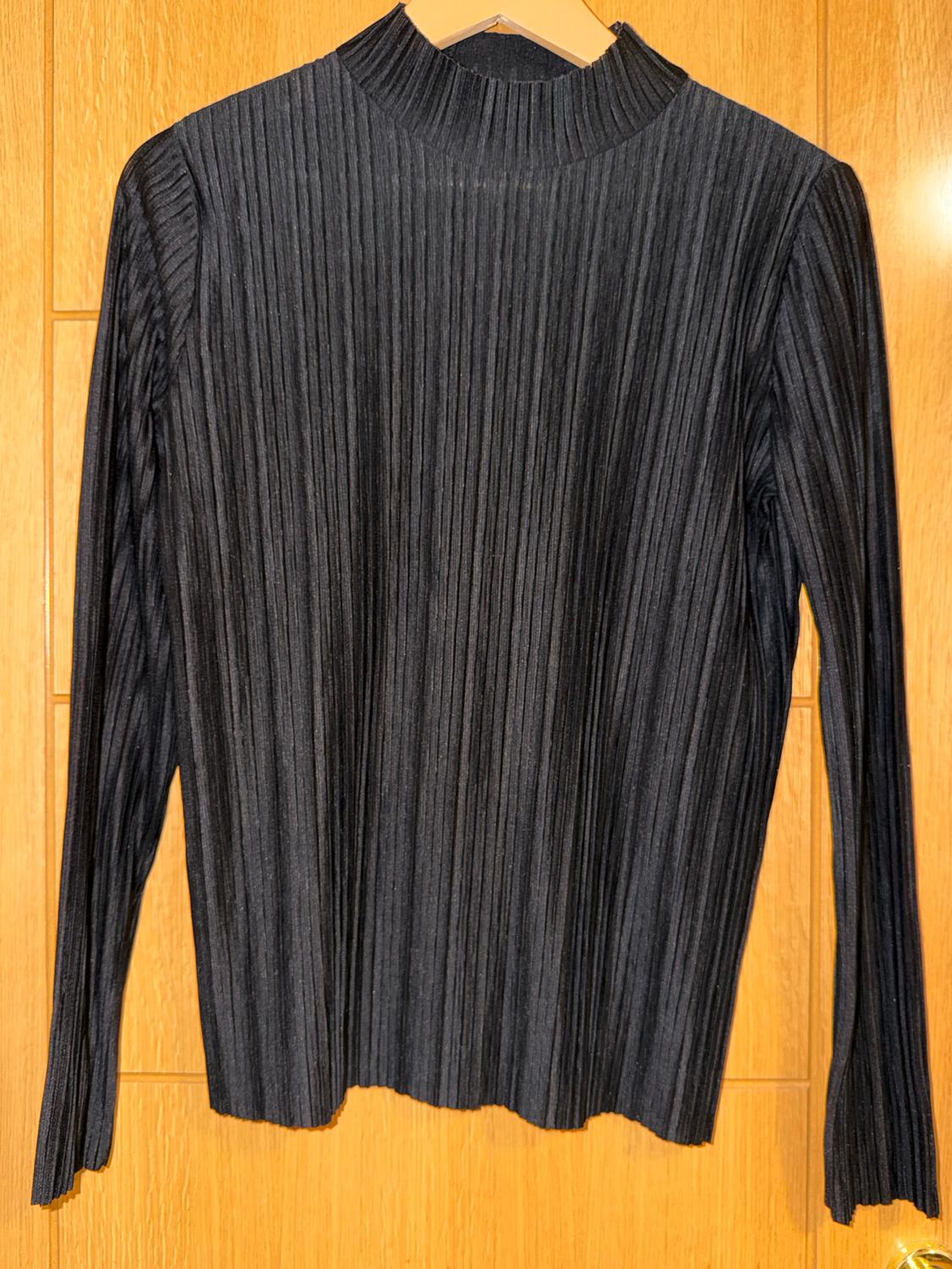 Black, long-sleeved, ribbed-knit jumper, hanging on a wooden hanger against a light wood background.