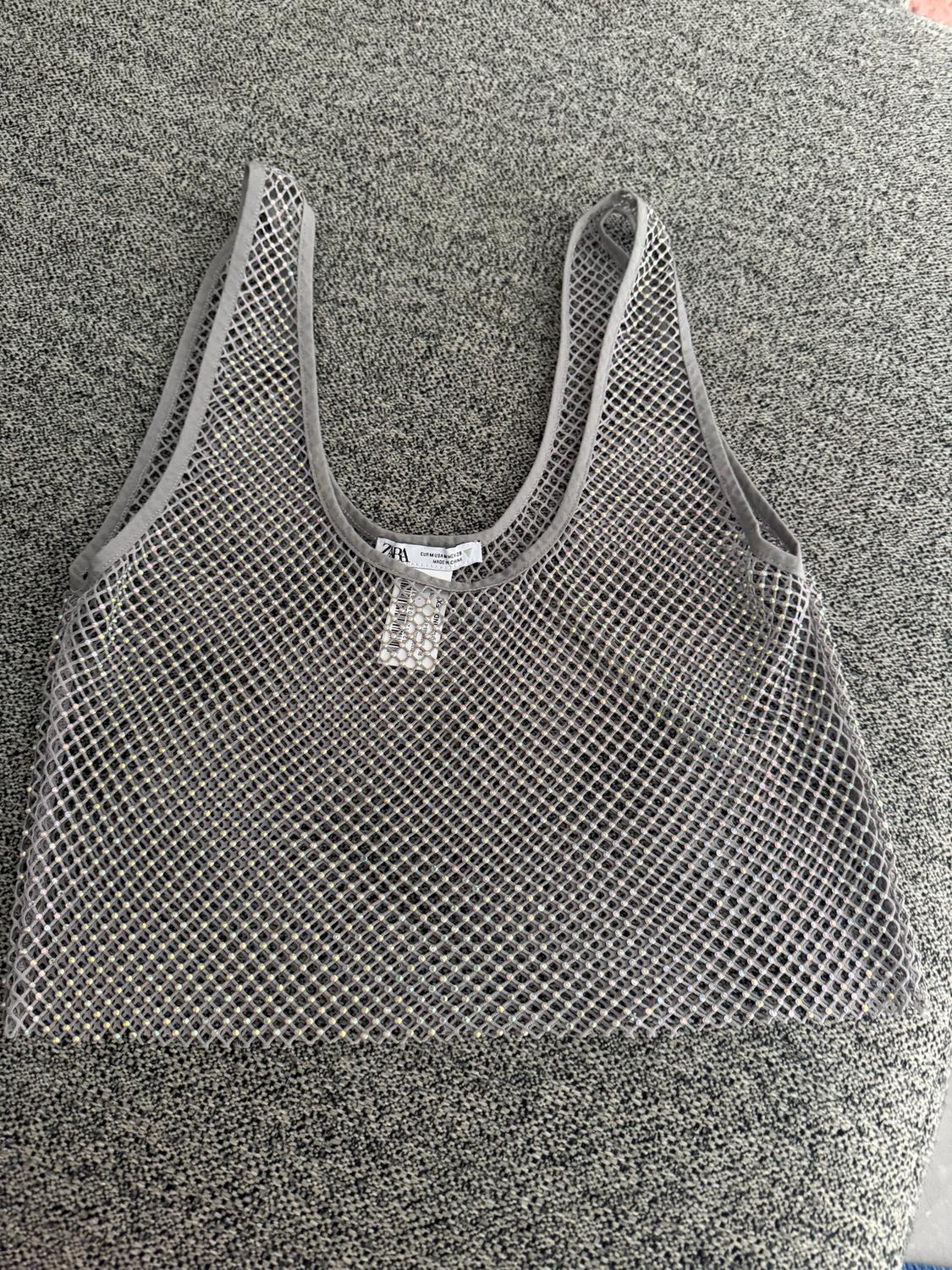 Grey mesh top with visible label on textured grey background.