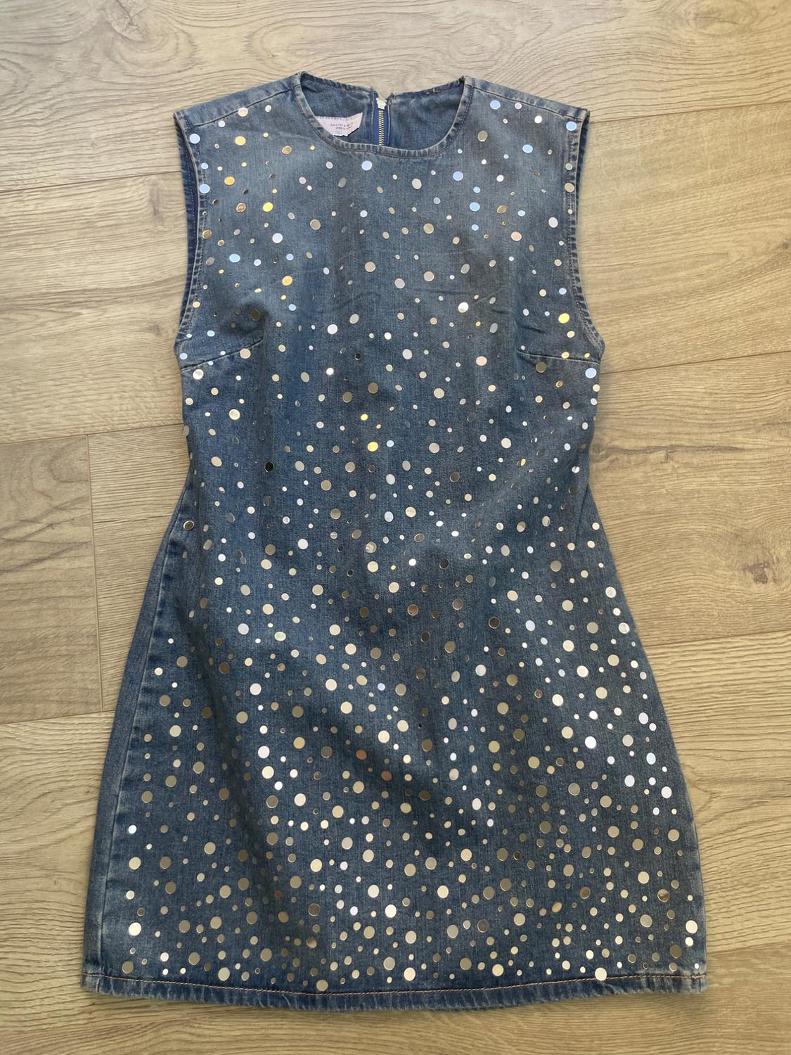 Sleeveless denim dress with metallic polka dot print on a light wood background.