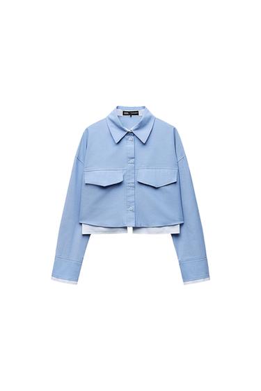 Front view of a short blue shirt with a classic collar and front pockets.