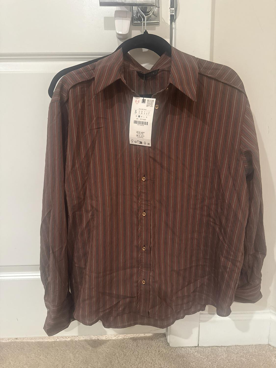 Long-sleeve shirt with vertical stripe print in brown tones, with a classic collar, front buttons, and a hanging price tag.