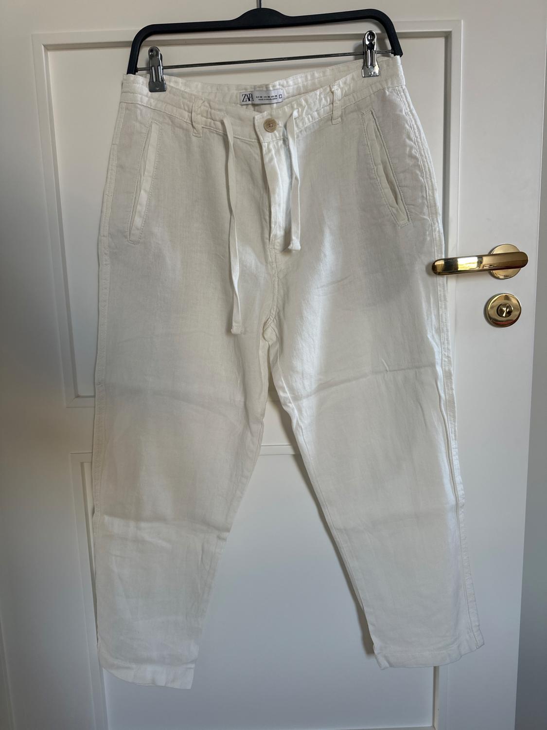 Front view of white trousers with side pockets and a drawstring waist.