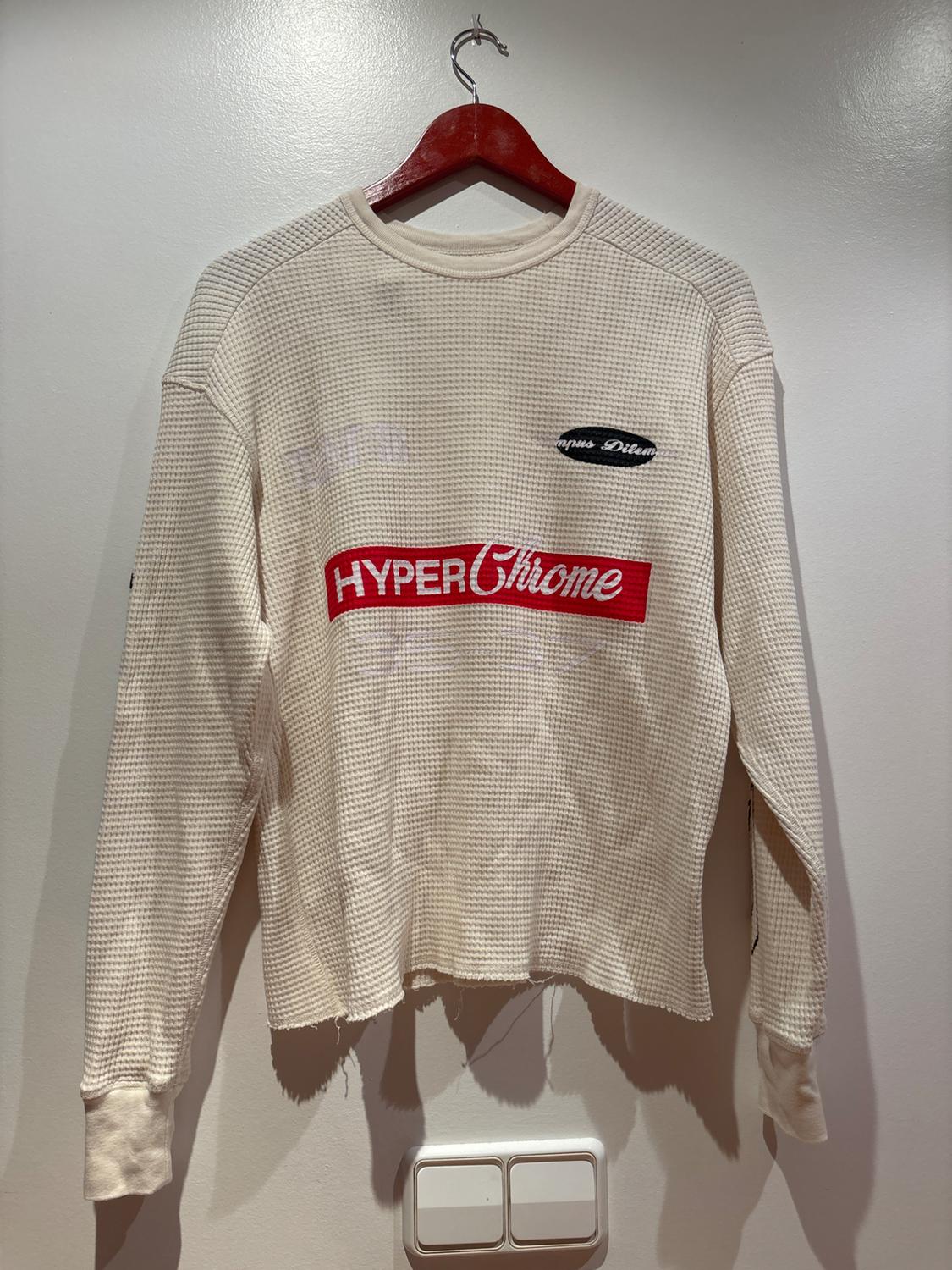 Cream textured T-shirt with frayed hem on a red hanger against a white wall. Text: HYPER Chrome, Campus Dilem.