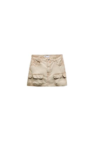 Front view of a beige skirt with flap and button front pockets.