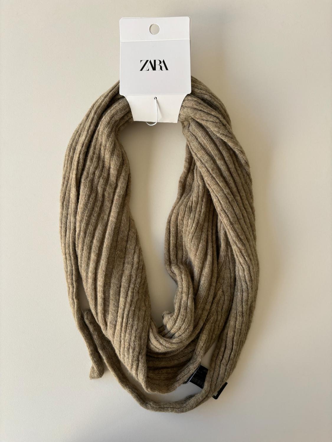 Beige ribbed knit scarf with visible 'ZARA' label.