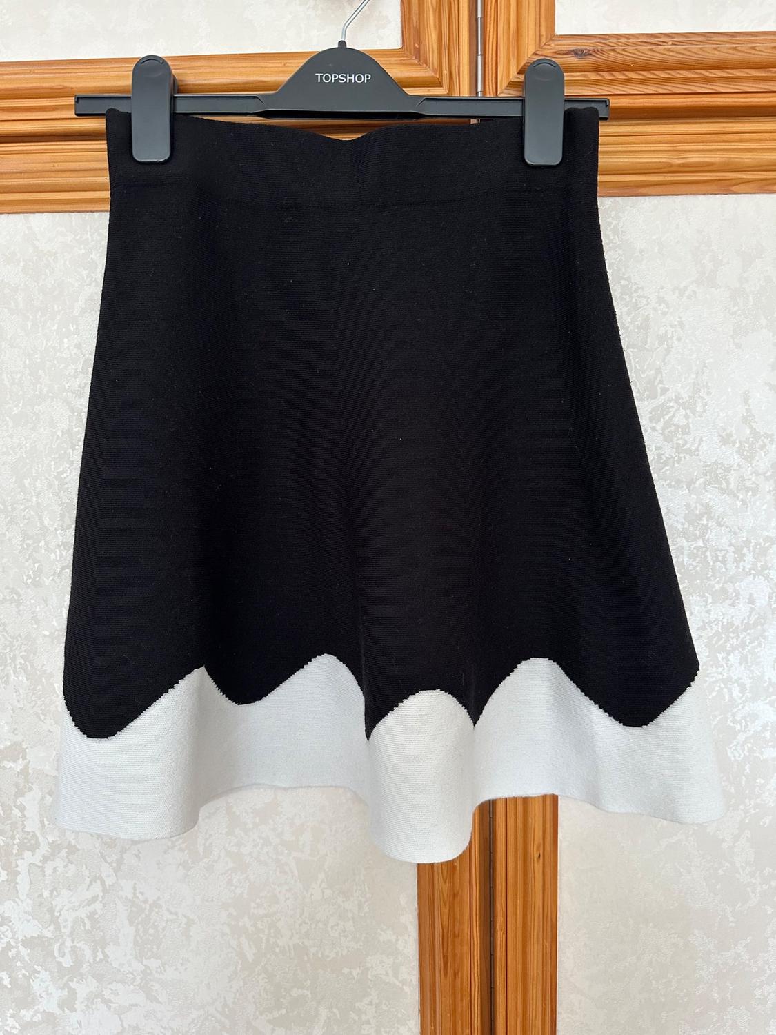 Front view of a black skirt with a wavy white hem.