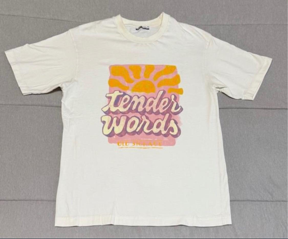 White t-shirt with sun design and "tender words" text in pink and orange on a grey background.