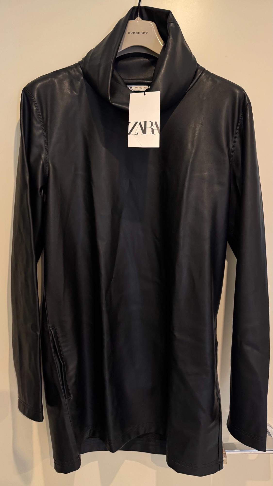 Black long-sleeved, high-neck garment on a hanger with the text BURBERRY and a label with the text ZARA.