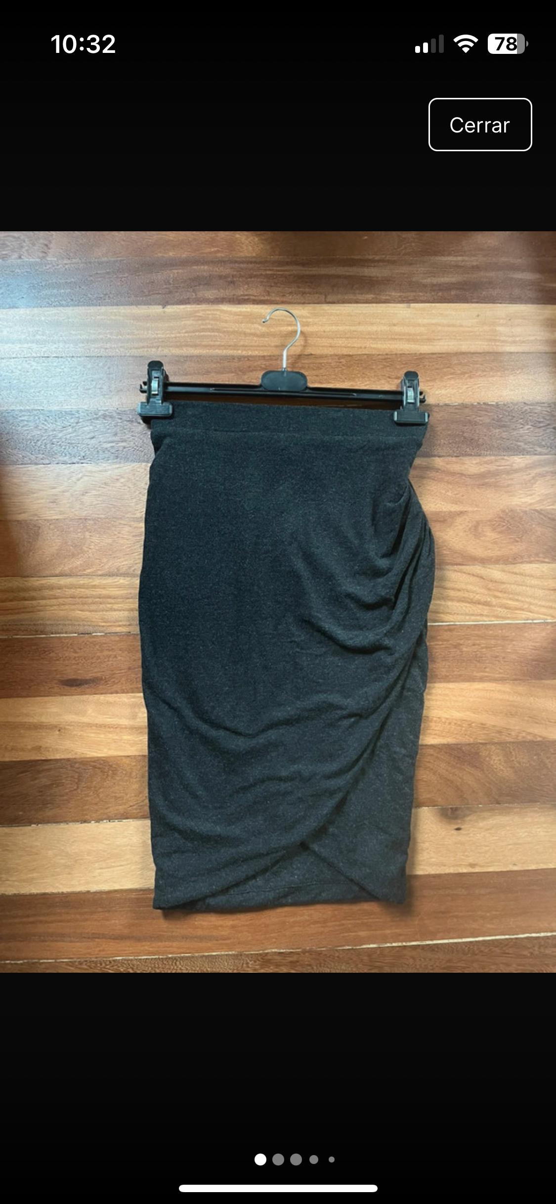 Front view of a black pleated skirt, hanging on a hanger.