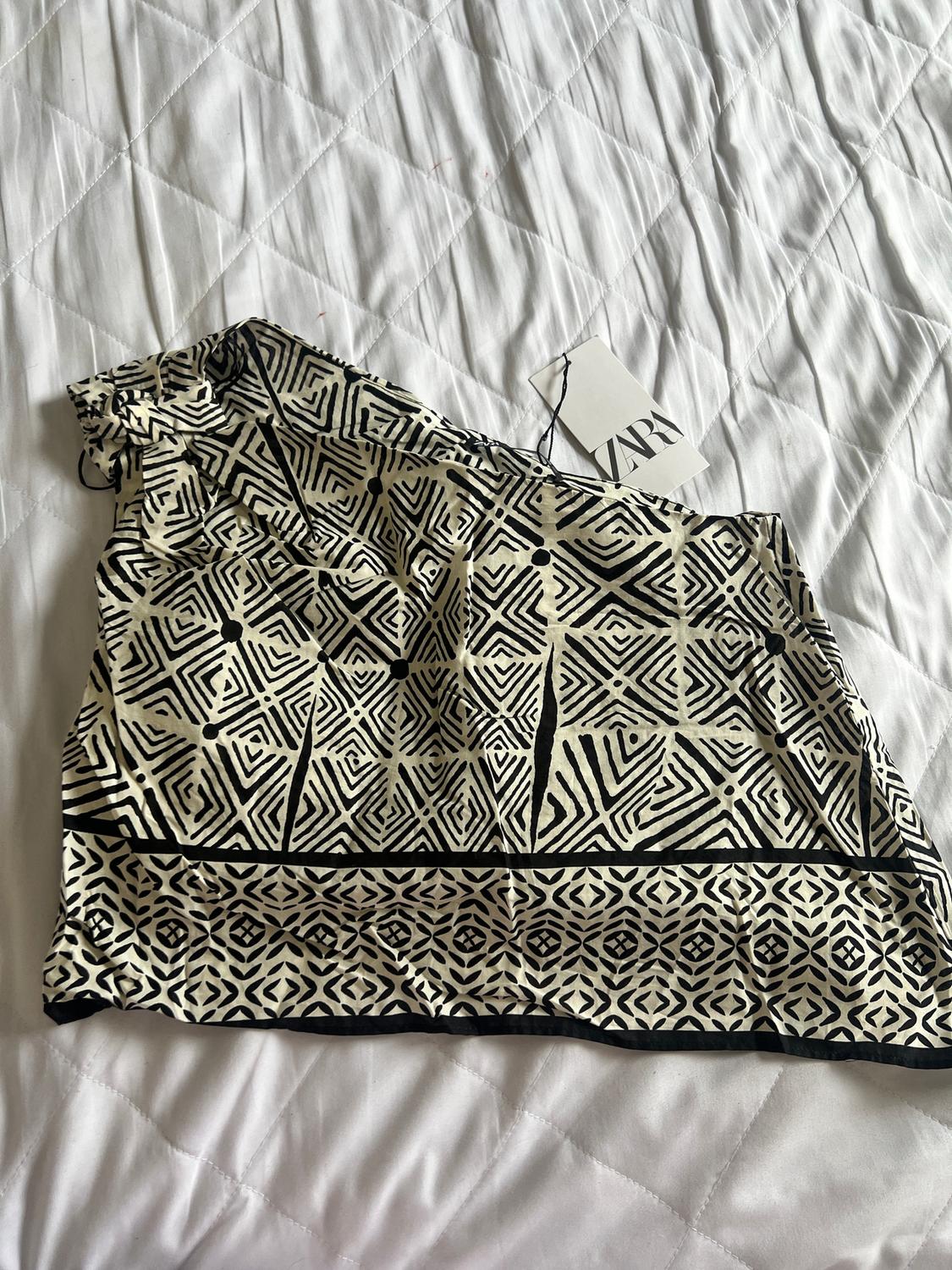 Black and white geometric print fabric on a white bed. Visible label with the text "ZARA".