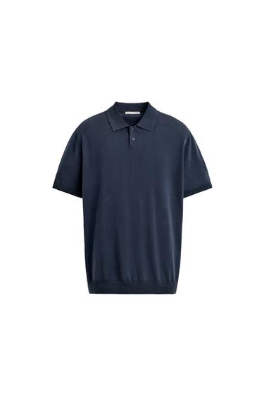 Front view of an indigo blue short-sleeved polo shirt, with a lapel collar, button placket, and ribbed cuffs and hem.