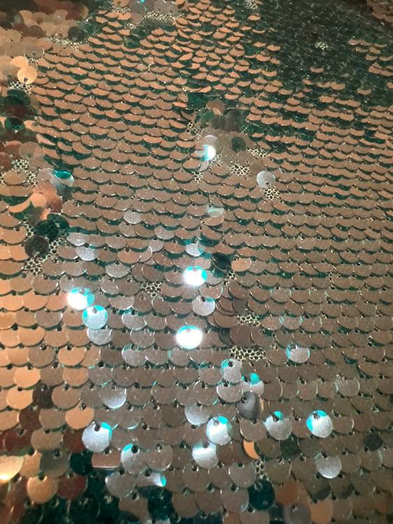 Shimmering gold and green sequined surface, creating a scaly effect with light reflections.