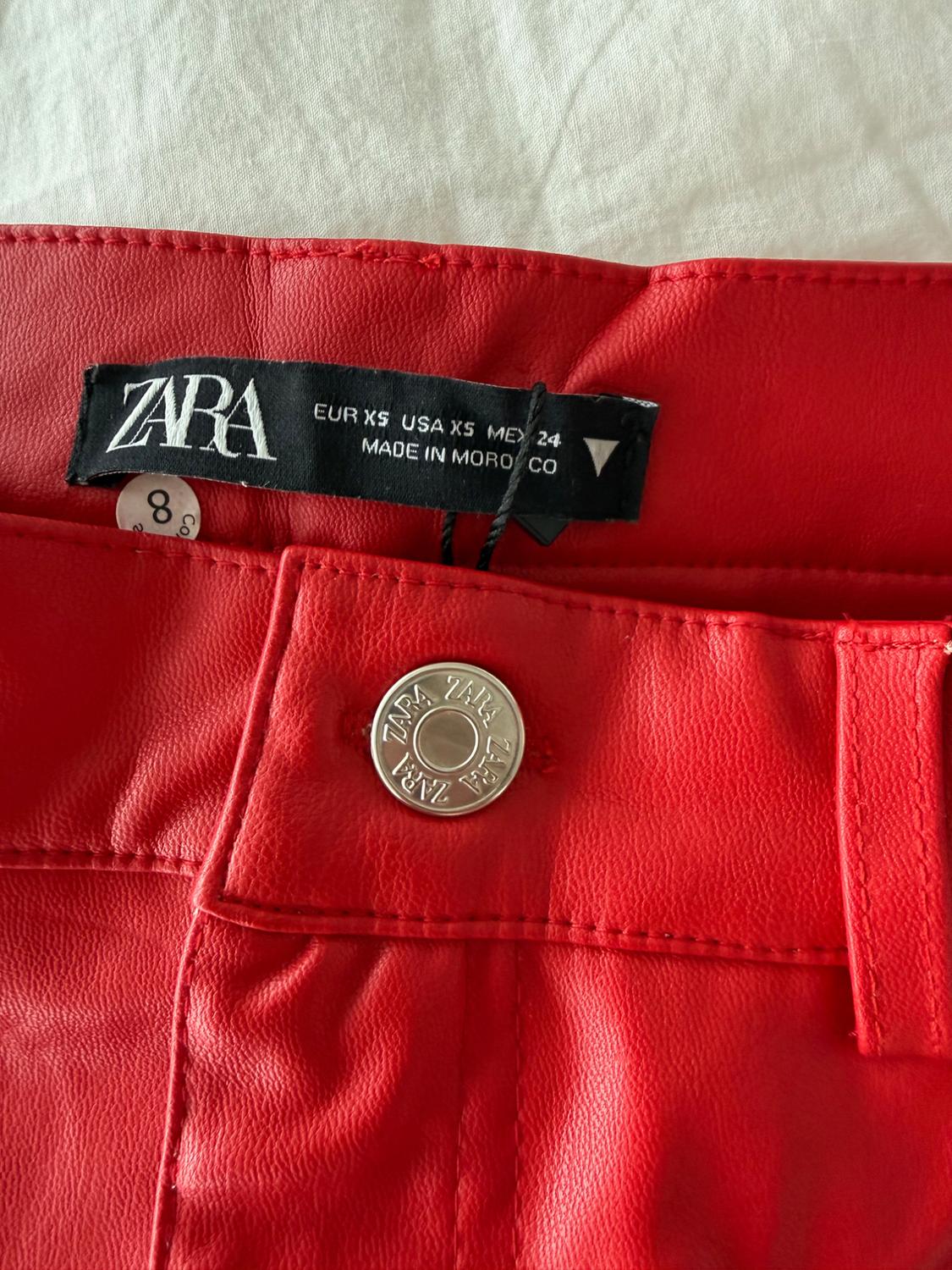 Zara red trousers label, size XS, made in Morocco. Metal button with visible Zara logo.