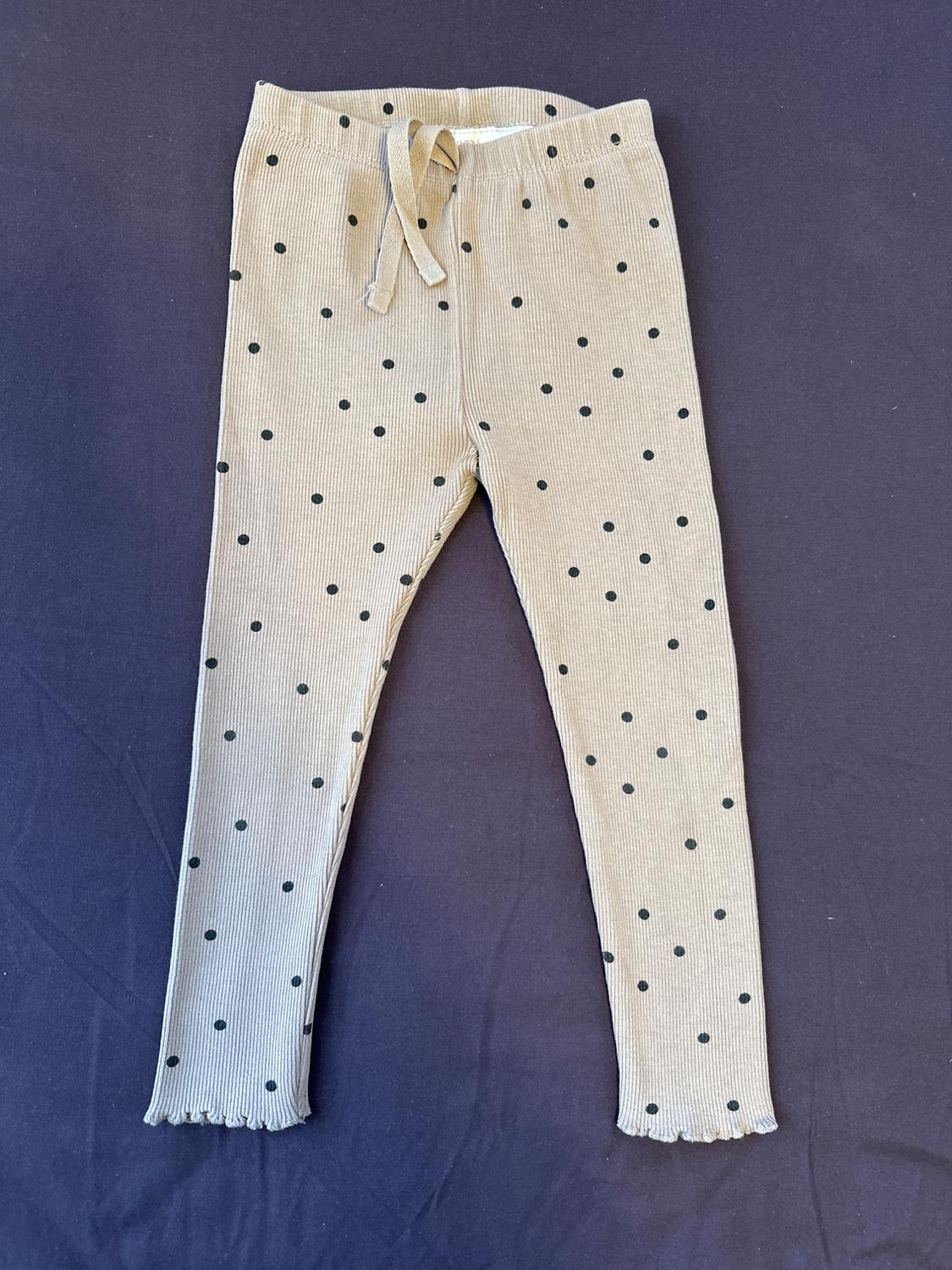 Front view of beige pants with black polka dots and a drawstring waist.