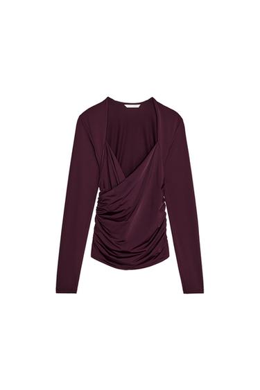 Front view of a burgundy blouse with draping at the front and long sleeves.