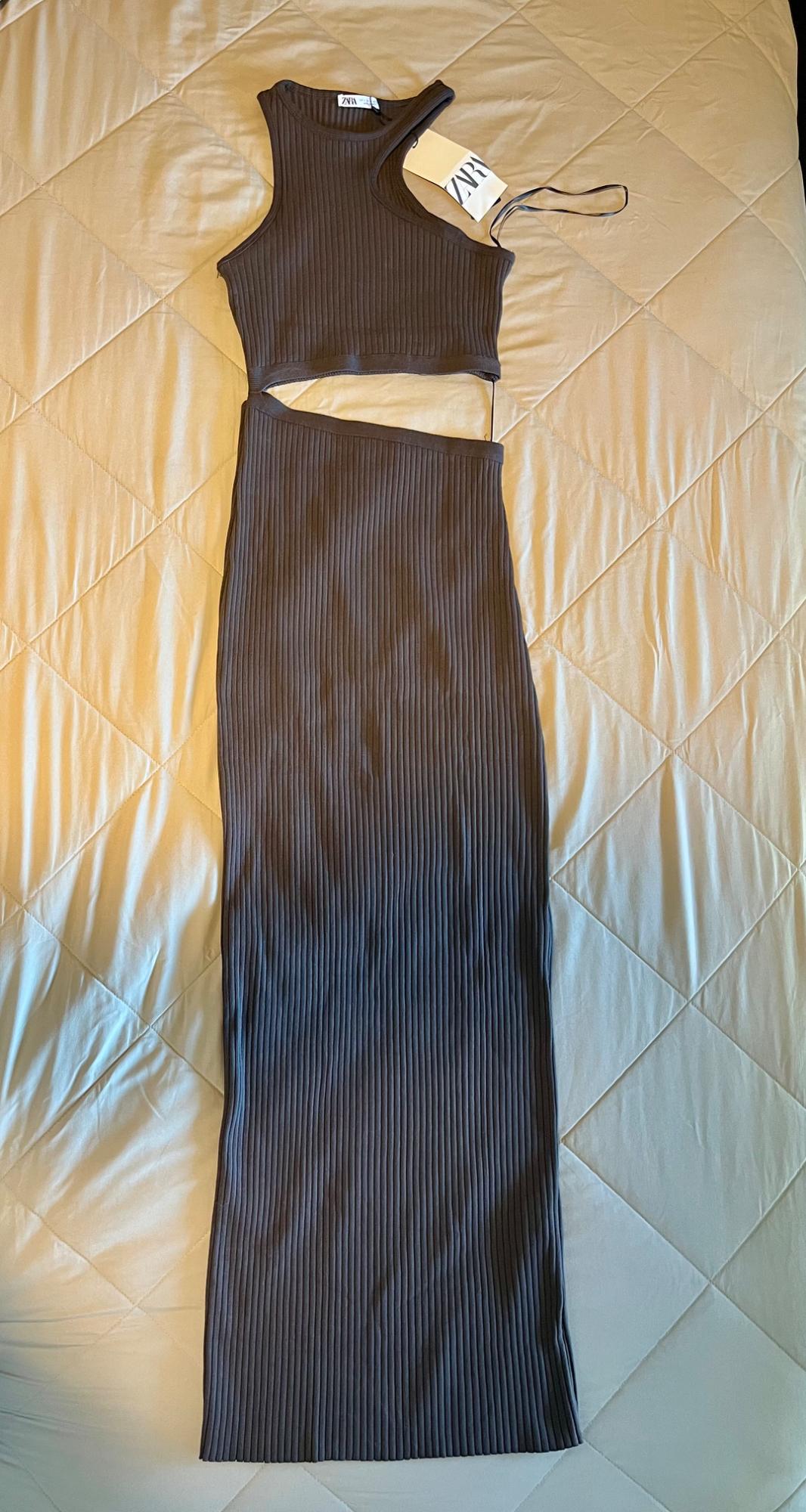 Dark brown sleeveless dress with side slits, visible tag on a quilted beige comforter.