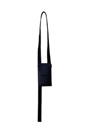 Front view of a black handbag with flap and long strap.