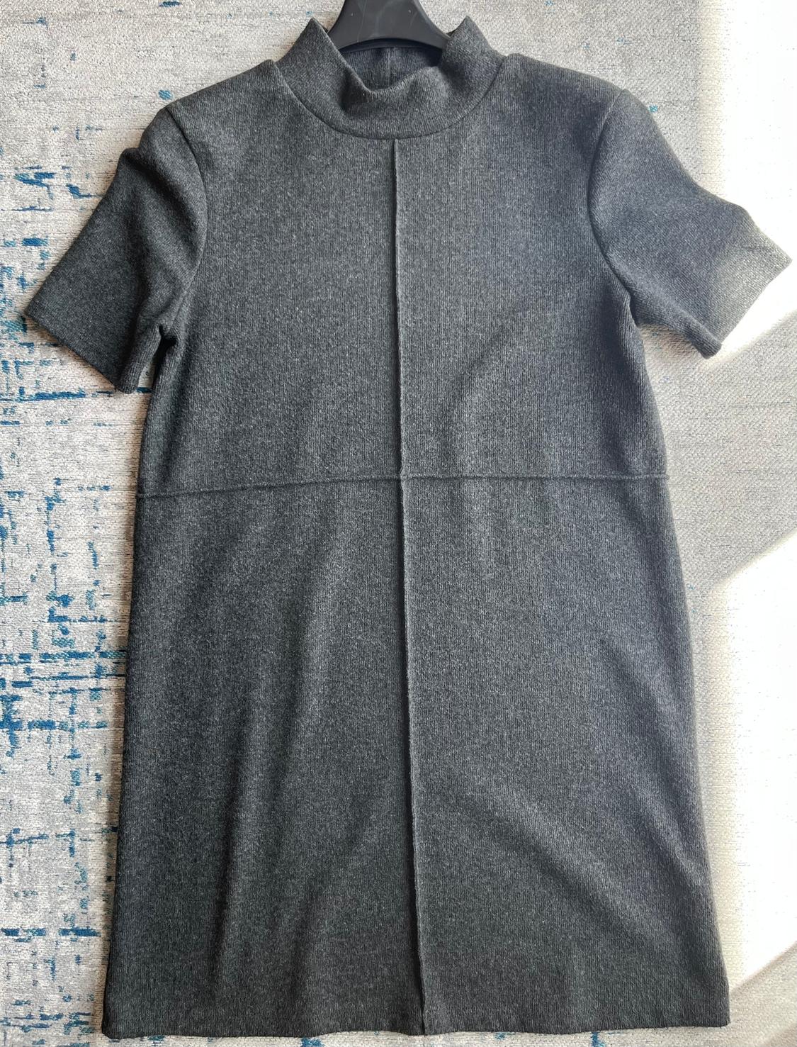 Grey short-sleeved, high-neck dress on a textured surface with blue details.