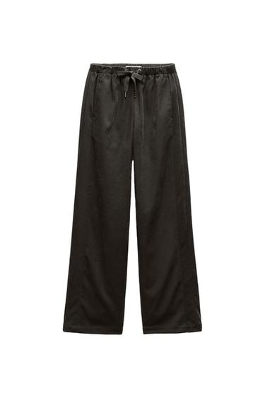 Black wide-leg trousers with an elasticated waist and adjustable drawstring, presented on a white background.