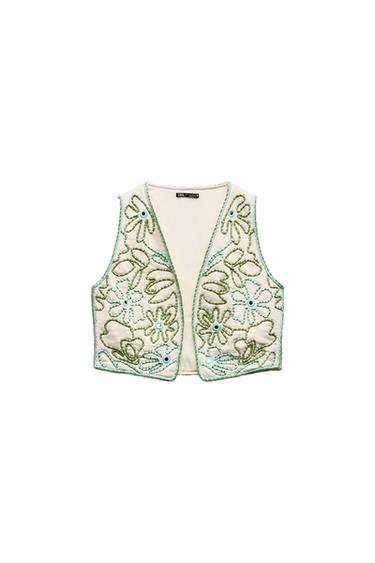 Front view of a white waistcoat with green and blue floral embroidery.