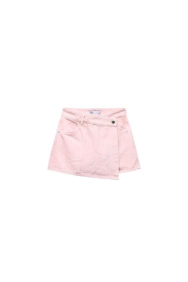 Light pink miniskirt with crossover design and button at the waist. Visible label on the inside of the waist. White background.