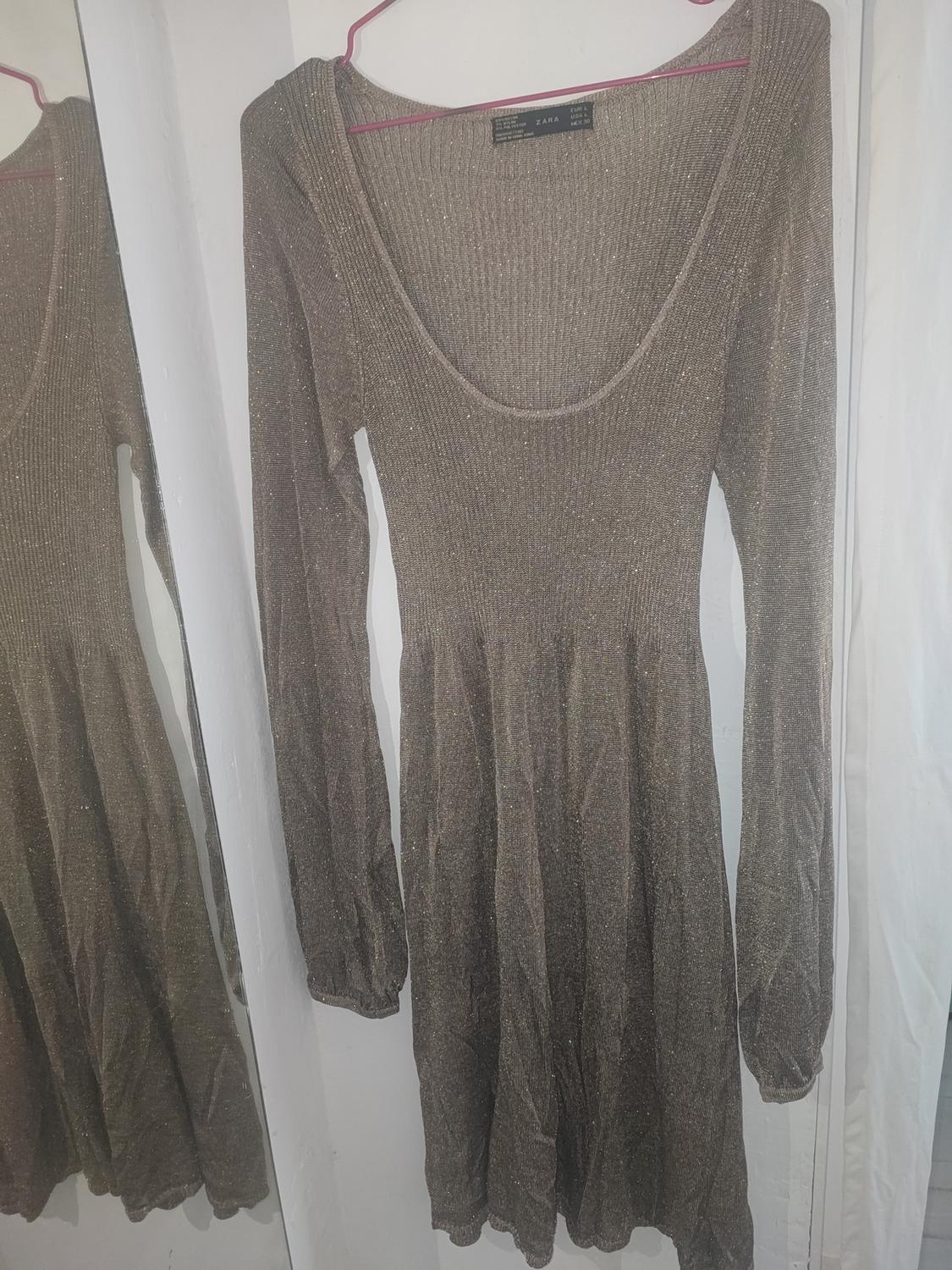 Brown long-sleeved glitter dress, hanging on a pink hanger in front of a mirror, reflecting its image.
