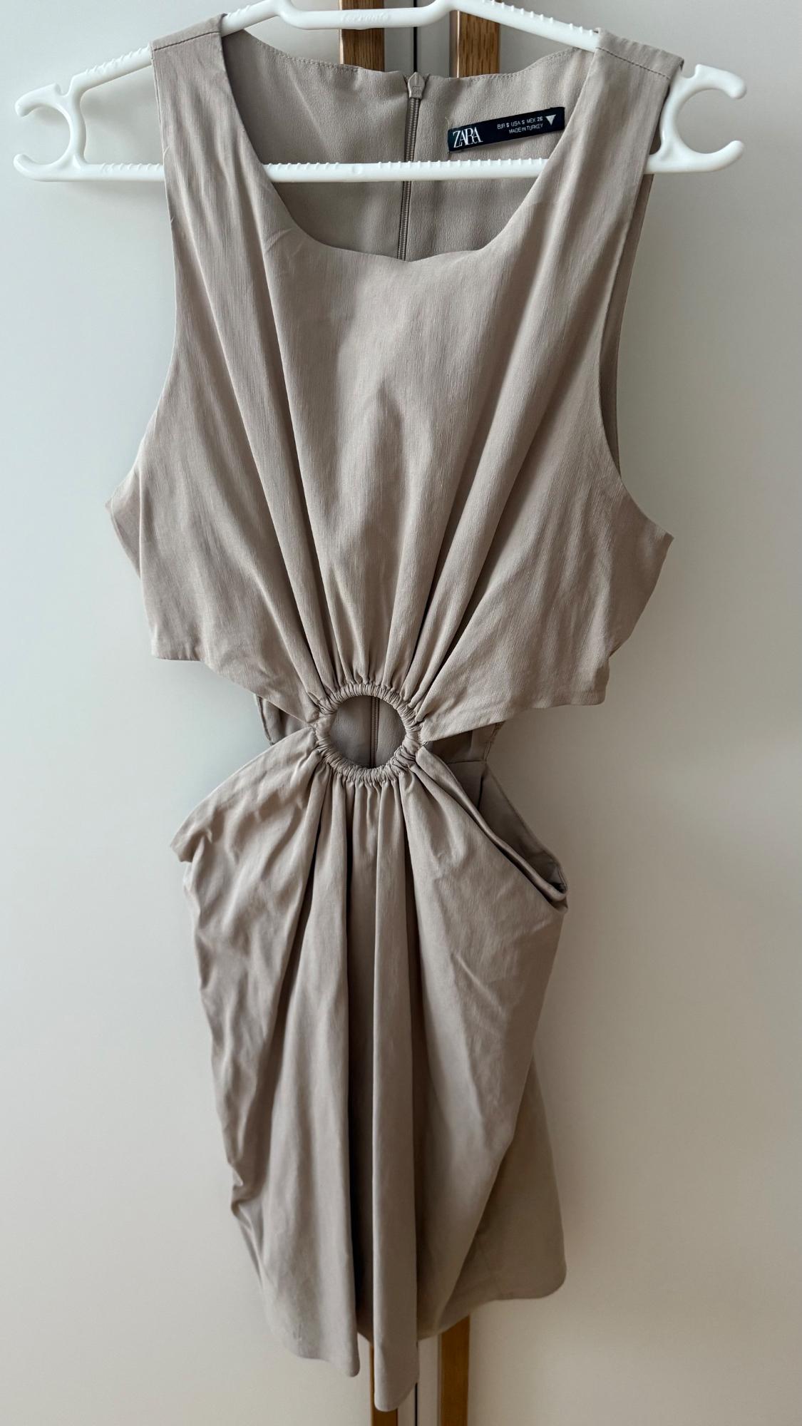 Beige sleeveless dress on a white hanger, with cut-outs and a central ring. Text: ZARA EUR S USA S MEX 26 MADE IN TURKEY.