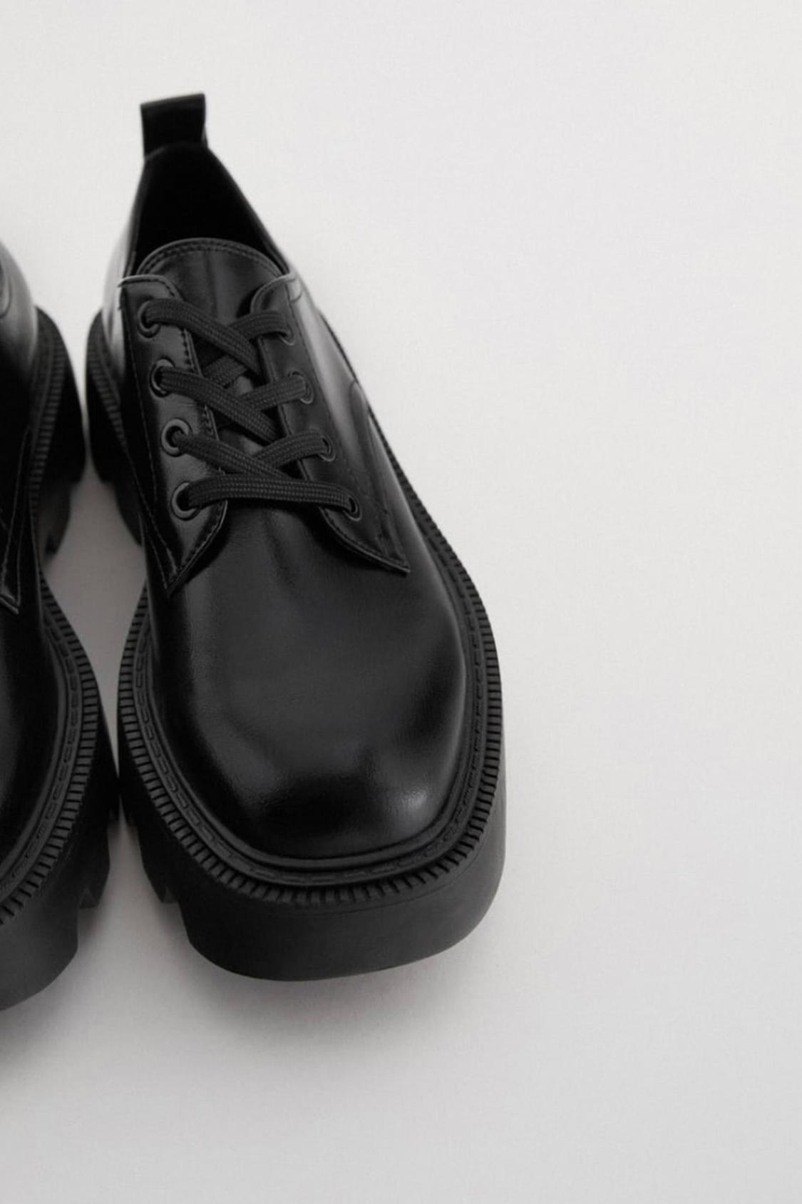 Detail of a black shoe with laces and a thick sole.