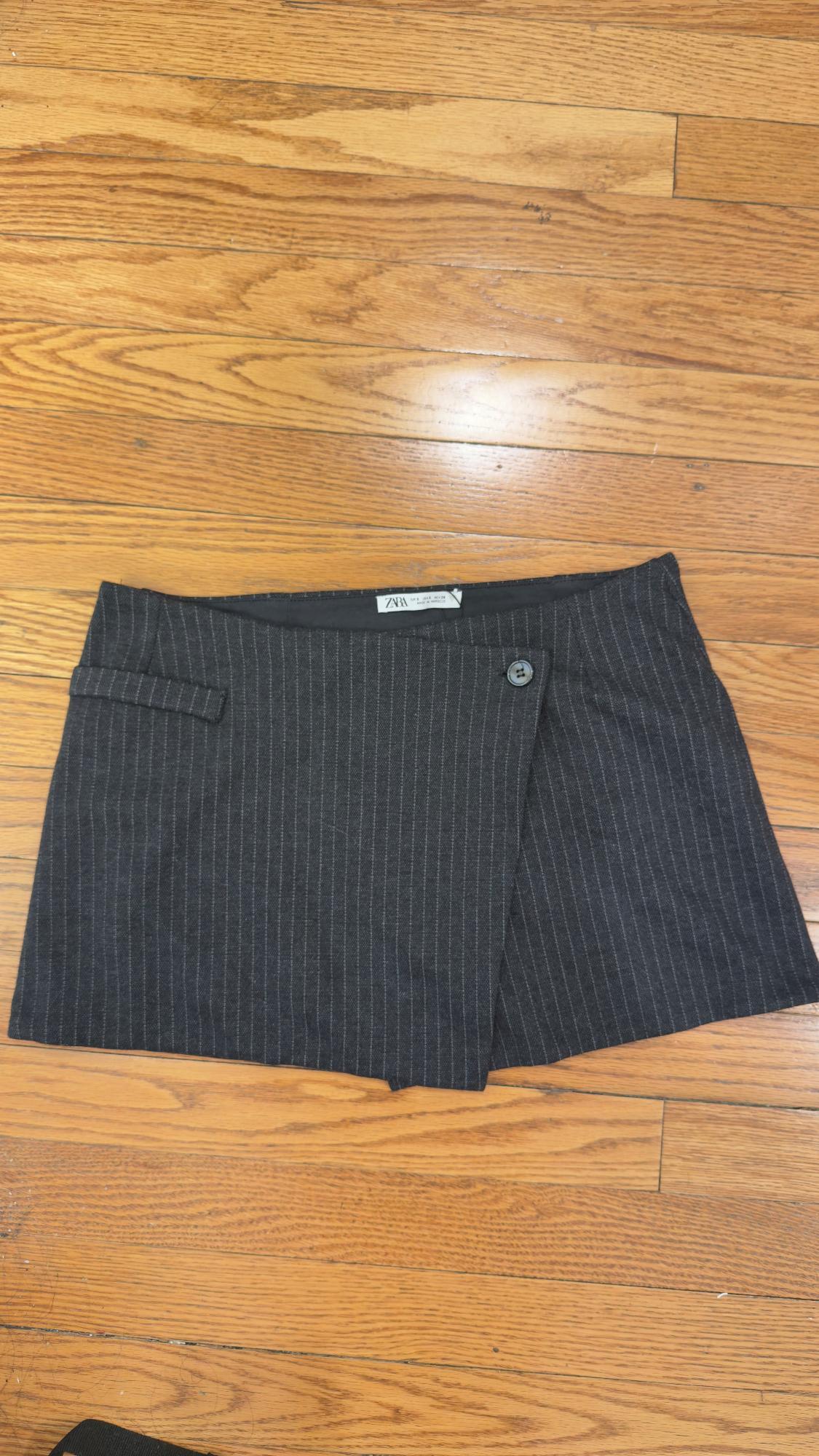 Gray striped fabric mini skirt with button, on a wooden floor. Visible label with text: "ZARA".